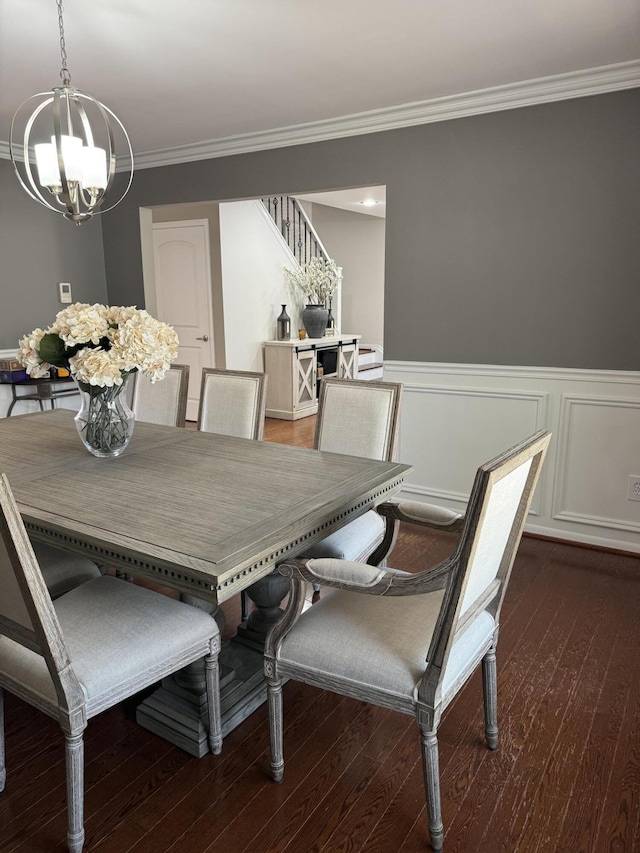 dining room featuring ornamental molding, stairs, wainscoting, wood finished floors, and a notable chandelier