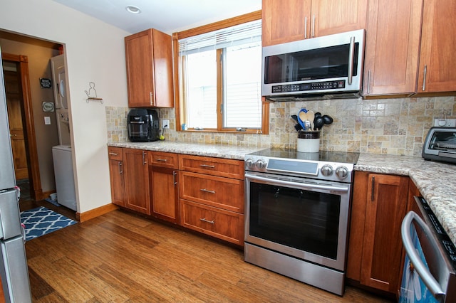 kitchen with decorative backsplash, appliances with stainless steel finishes, wood finished floors, and brown cabinets