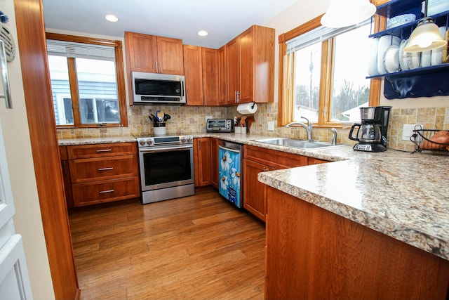 kitchen with a sink, light countertops, stainless steel appliances, wood finished floors, and tasteful backsplash