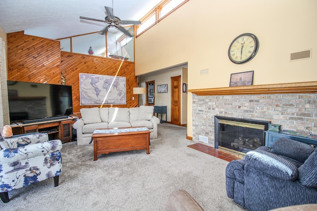 carpeted living area with a ceiling fan, a high ceiling, wood walls, and visible vents