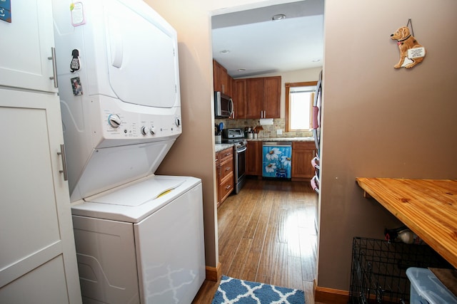 laundry room with laundry area, stacked washer / dryer, and wood finished floors
