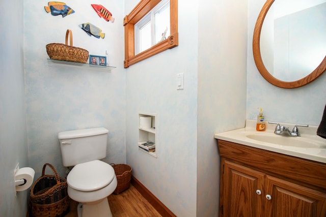 bathroom featuring toilet, baseboards, wood finished floors, and vanity