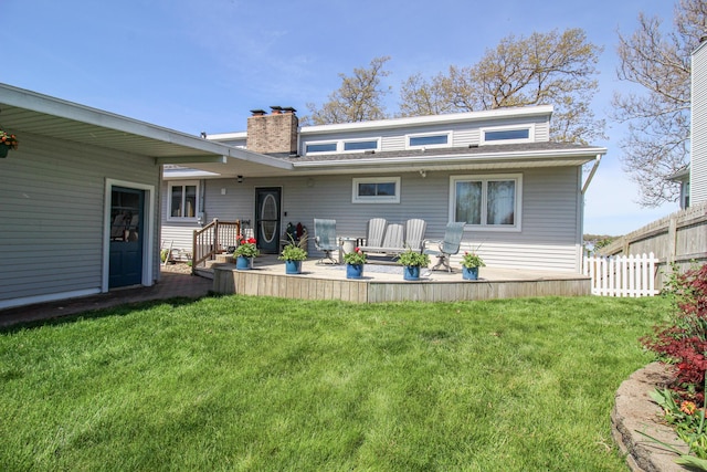 back of property with a yard, fence, a chimney, and a patio area
