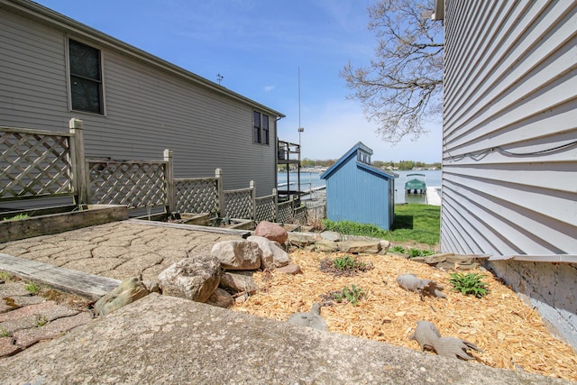 view of side of property with an outbuilding, fence, and a storage shed