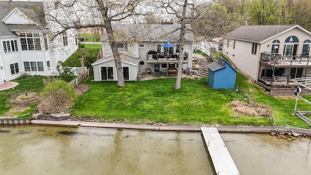 rear view of property with a storage shed, fence, an outbuilding, and a deck with water view