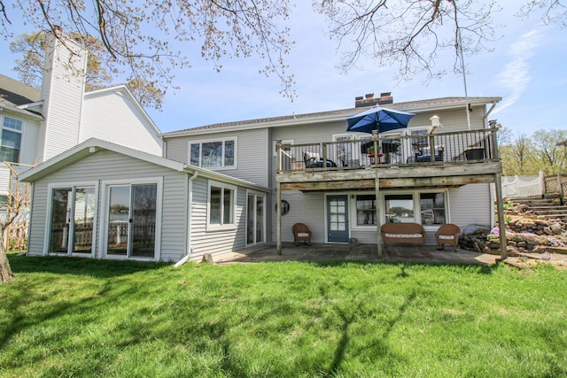 back of property with a yard, a patio, a wooden deck, and a chimney