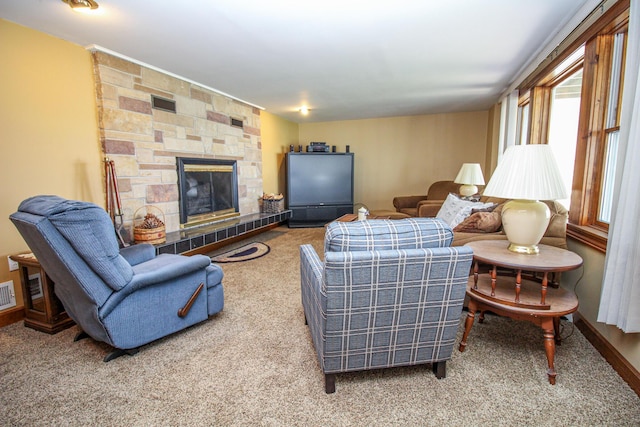 carpeted living area with a stone fireplace and visible vents