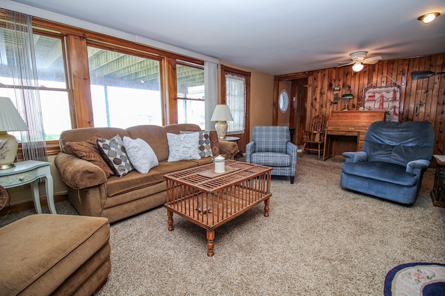 carpeted living room featuring wooden walls and a ceiling fan