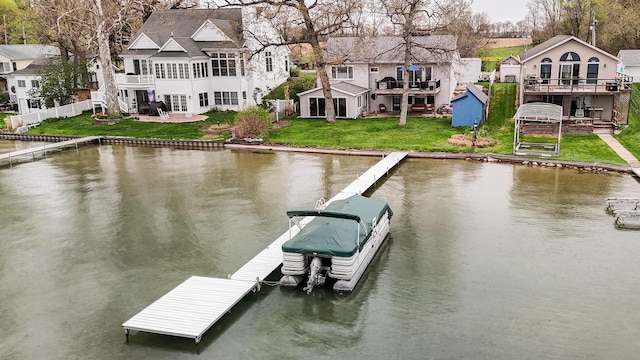 view of dock featuring a lawn, fence, a residential view, and a deck with water view