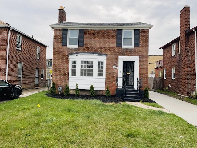 view of front facade featuring brick siding, a chimney, and a front lawn