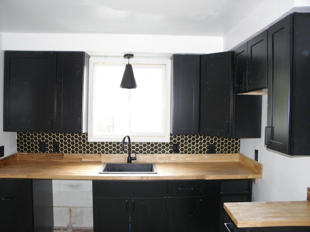 19209 Hartwell St, Detroit, MI 48235 - kitchen with wood counters, a sink, dark cabinets, tasteful backsplash, and decorative light fixtures