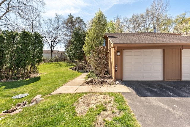 view of side of property with a lawn, a shingled roof, and a garage