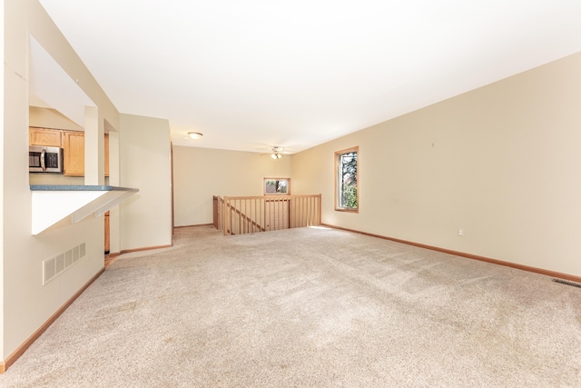 unfurnished living room with baseboards, visible vents, and light carpet