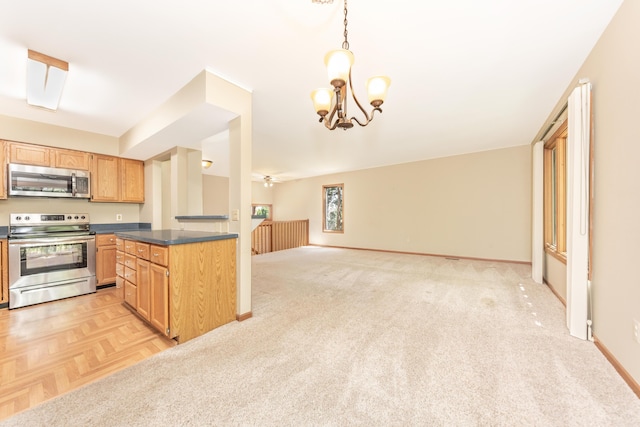 kitchen with decorative light fixtures, dark countertops, appliances with stainless steel finishes, baseboards, and open floor plan