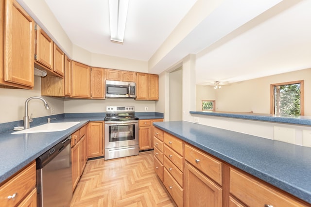 kitchen with a sink, ceiling fan, dark countertops, and stainless steel appliances