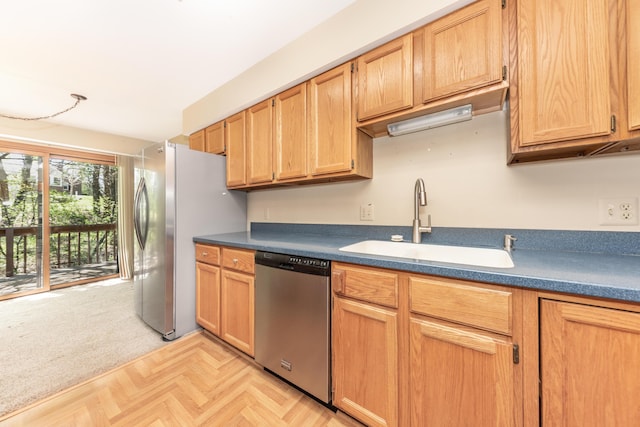 kitchen featuring light colored carpet, dark countertops, appliances with stainless steel finishes, and a sink