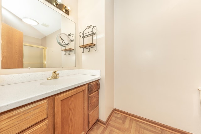 full bathroom with vanity, baseboards, and a shower with door