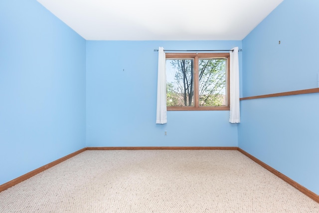 carpeted spare room featuring baseboards
