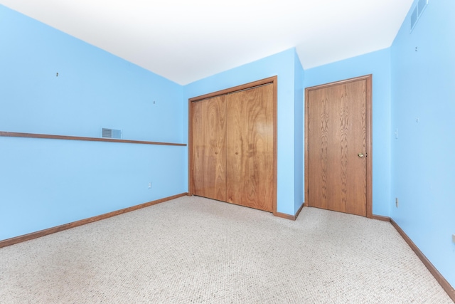 unfurnished bedroom featuring a closet, baseboards, light colored carpet, and visible vents