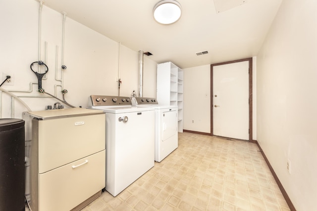 clothes washing area with washer and dryer, laundry area, baseboards, light floors, and visible vents