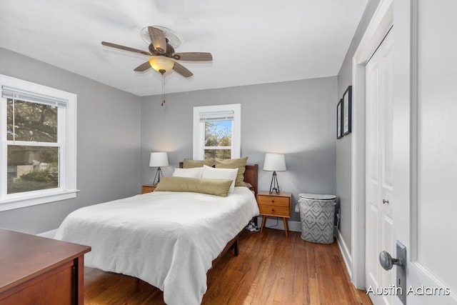 bedroom featuring dark wood-style flooring, baseboards, ceiling fan, and a closet