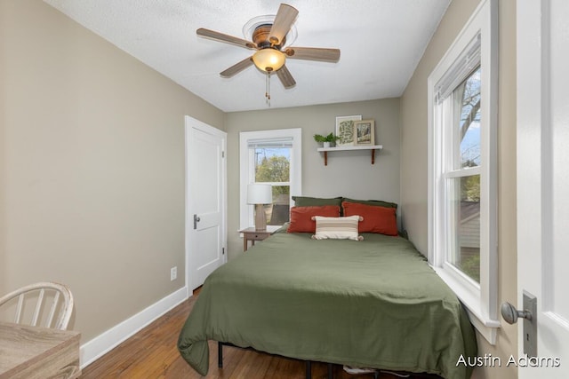 bedroom featuring a ceiling fan, baseboards, and wood finished floors