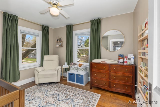 bedroom with baseboards, ceiling fan, wood finished floors, and multiple windows