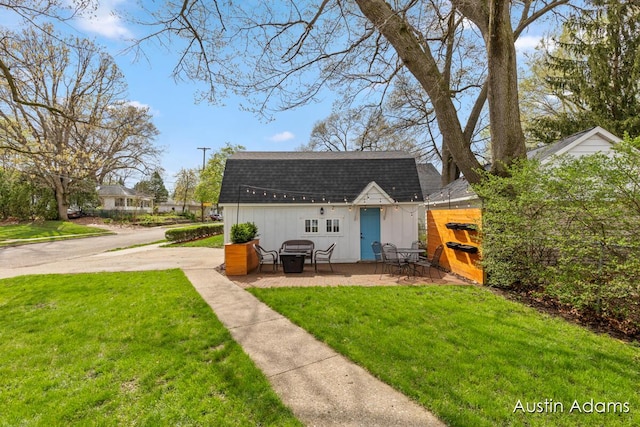 rear view of house with roof with shingles, an outbuilding, and a yard