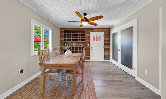 1205 Mckail Rd, Leonard, MI 48367 - dining room featuring wooden walls, wood ceiling, ceiling fan, wood finished floors, and baseboards