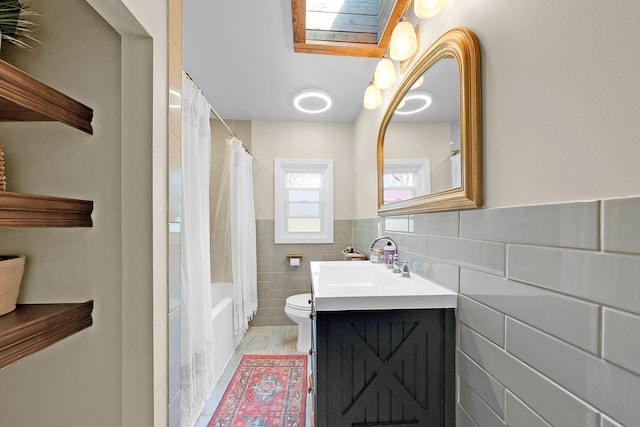 1205 Mckail Rd, Leonard, MI 48367 - full bathroom featuring tile walls, a skylight, toilet, vanity, and a wainscoted wall
