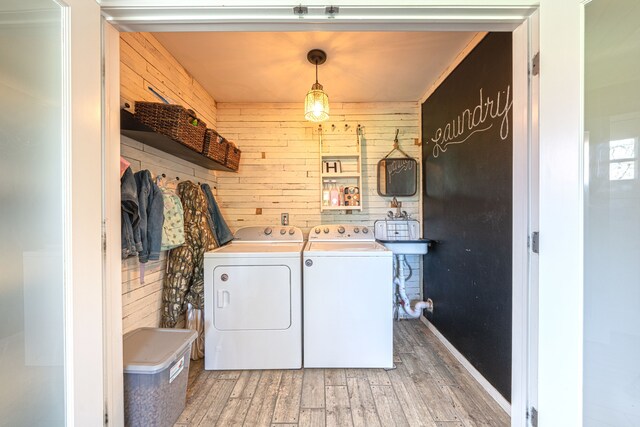 1205 Mckail Rd, Leonard, MI 48367 - clothes washing area with washing machine and clothes dryer, wooden walls, and light wood-type flooring