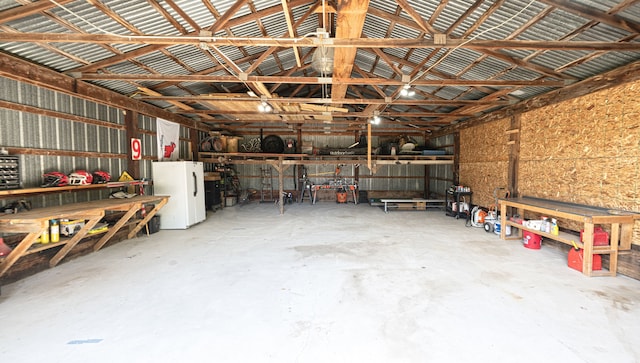 1205 Mckail Rd, Leonard, MI 48367 - garage featuring freestanding refrigerator and a workshop area