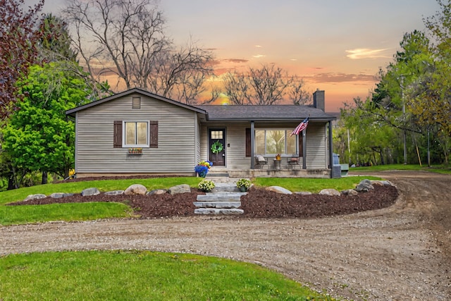 1205 Mckail Rd, Leonard, MI 48367 - view of front of home featuring a chimney, dirt driveway, a porch, a lawn, and a shingled roof