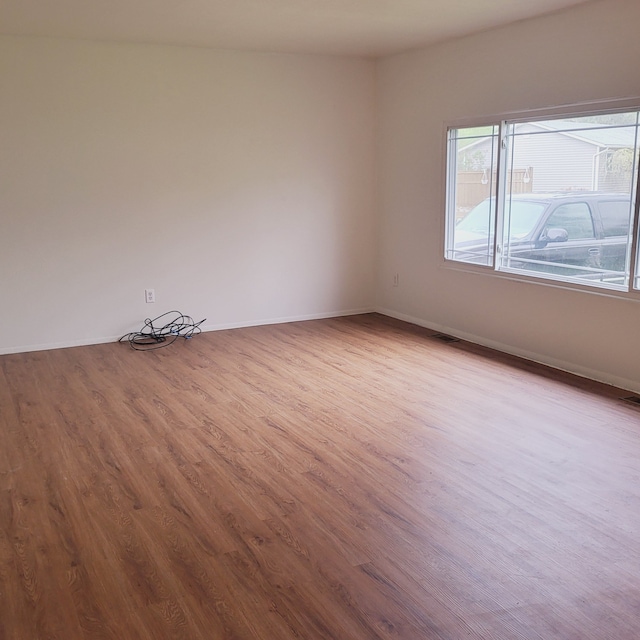 unfurnished room with baseboards and wood finished floors