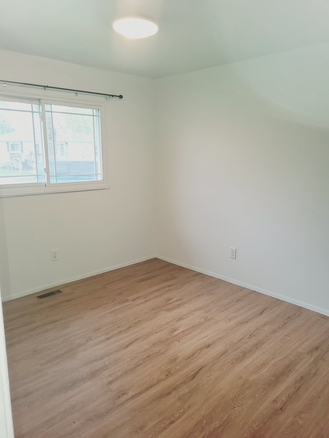 unfurnished room featuring baseboards, light wood-type flooring, and visible vents