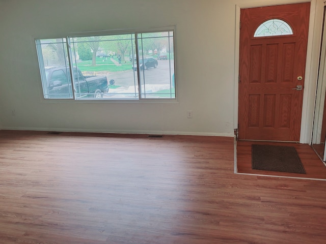foyer featuring baseboards, wood finished floors, and visible vents