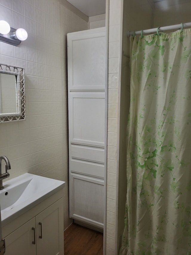bathroom featuring a shower with shower curtain, tile walls, wood finished floors, and vanity
