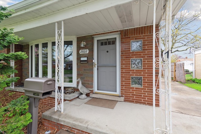 property entrance featuring a porch and brick siding