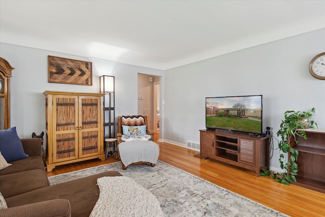 living room featuring baseboards, visible vents, and wood finished floors