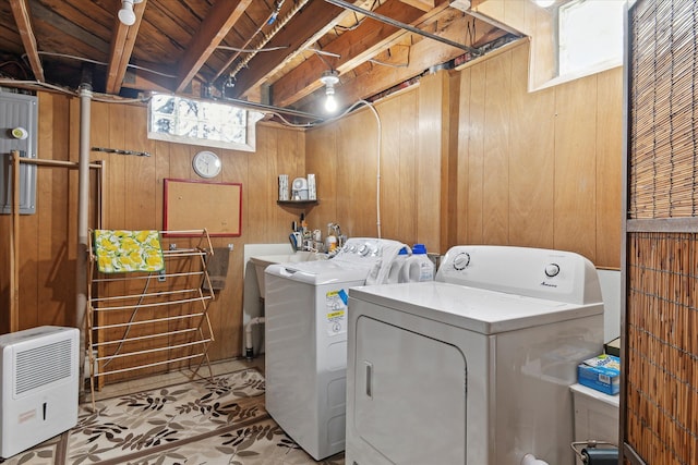 clothes washing area with washing machine and clothes dryer, laundry area, wooden walls, and a sink