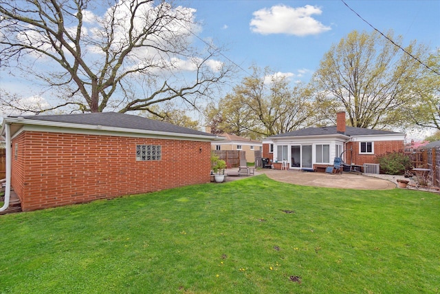 back of property featuring a patio, a chimney, a lawn, fence, and brick siding
