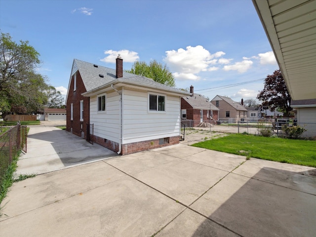 rear view of house featuring an outdoor structure, fence, a chimney, a shingled roof, and a lawn