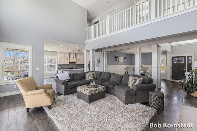 3779 Mesa Verde Dr, Hudsonville, MI 49426 - living area featuring ornate columns, wainscoting, dark wood finished floors, and a towering ceiling