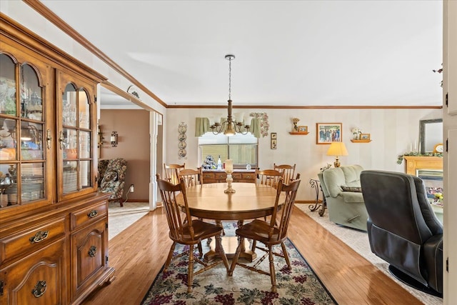 dining room featuring baseboards, a notable chandelier, ornamental molding, and light wood-style flooring