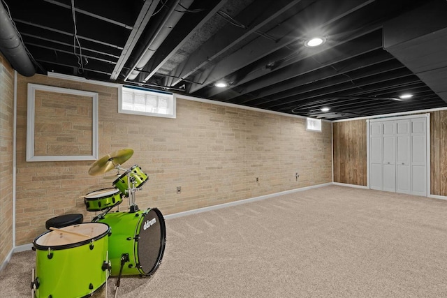 basement featuring baseboards, carpet flooring, and brick wall