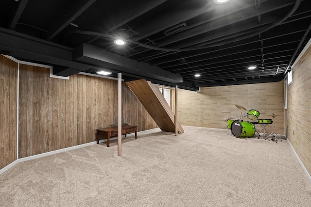 basement featuring baseboards, carpet flooring, wooden walls, and brick wall