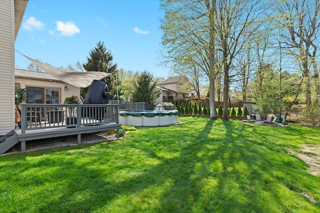 view of yard featuring a fenced backyard, a covered pool, a deck, and an outdoor fire pit