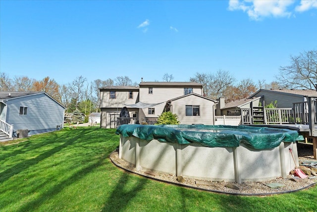 back of property with a lawn, a covered pool, and a deck