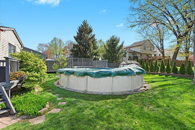 view of swimming pool with a lawn, fence, and a covered pool