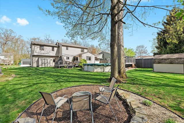 view of yard featuring a storage unit, a covered pool, a deck, an outbuilding, and a fire pit